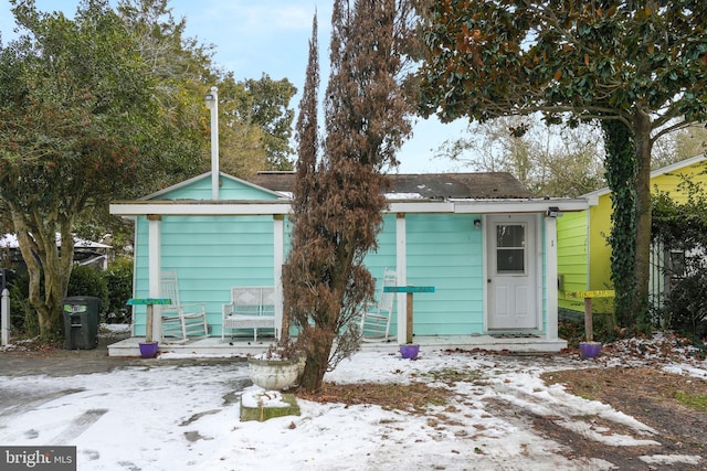 snow covered rear of property with a shed