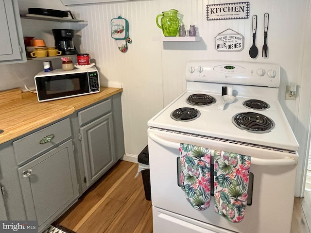 kitchen featuring electric range, butcher block countertops, hardwood / wood-style flooring, and gray cabinetry