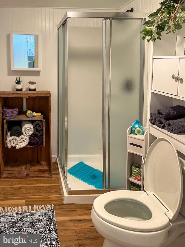 bathroom featuring a shower with shower door, toilet, and wood-type flooring