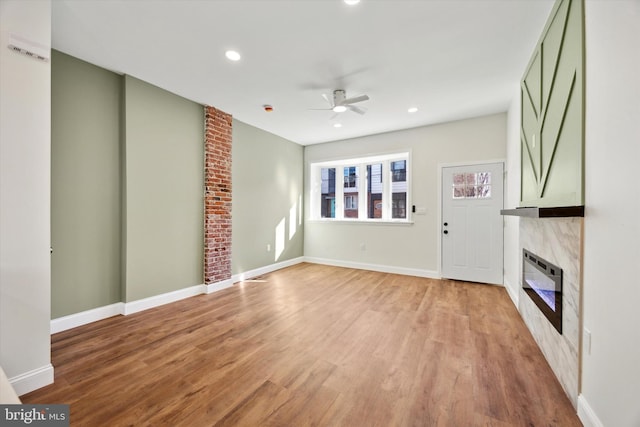 unfurnished living room featuring ceiling fan, a premium fireplace, and light hardwood / wood-style flooring