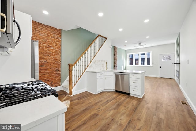 kitchen featuring kitchen peninsula, light wood-type flooring, ceiling fan, dishwasher, and white cabinetry