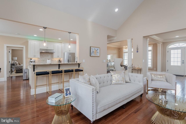 living room featuring dark hardwood / wood-style flooring, ornate columns, a wealth of natural light, and lofted ceiling