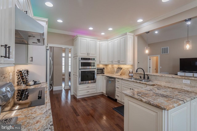 kitchen featuring light stone counters, sink, pendant lighting, white cabinets, and range hood