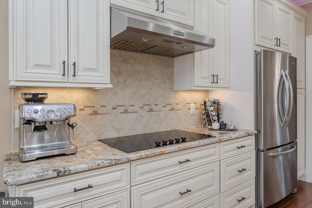 kitchen with stainless steel fridge, black electric cooktop, white cabinetry, and tasteful backsplash