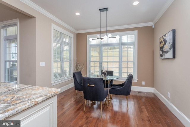 dining room featuring plenty of natural light, dark hardwood / wood-style flooring, ornamental molding, and an inviting chandelier