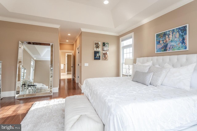 bedroom featuring ornamental molding, a tray ceiling, and dark wood-type flooring