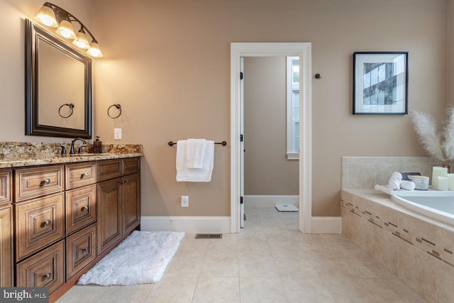 bathroom with tile patterned floors, tiled bath, and vanity