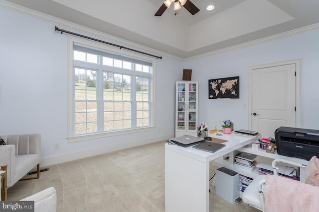 carpeted office space with a tray ceiling, crown molding, and ceiling fan