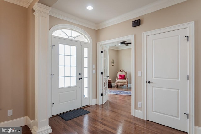 entryway featuring ceiling fan, crown molding, ornate columns, and dark wood-type flooring