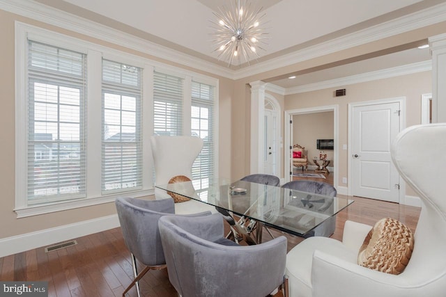 dining space with decorative columns, hardwood / wood-style flooring, a notable chandelier, and ornamental molding