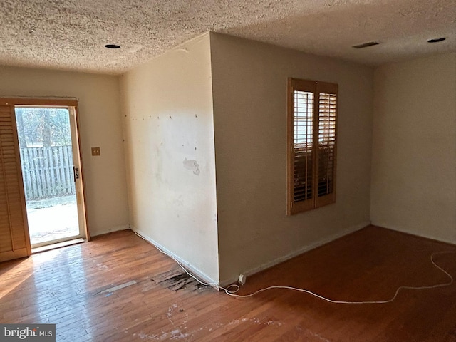 unfurnished room with hardwood / wood-style floors, a textured ceiling, and a healthy amount of sunlight