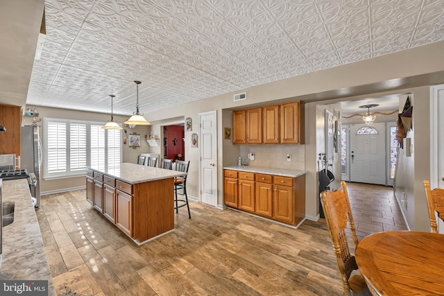 kitchen with light stone countertops, a center island, backsplash, pendant lighting, and a breakfast bar