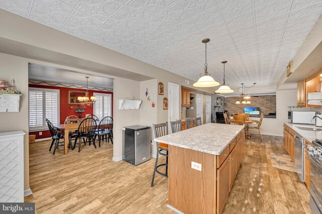 kitchen featuring a center island, sink, stainless steel appliances, light hardwood / wood-style flooring, and decorative light fixtures