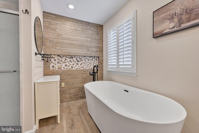 bathroom featuring hardwood / wood-style flooring, a bathtub, and tile walls