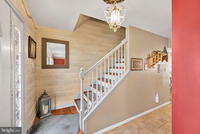 stairs featuring wooden walls and a chandelier