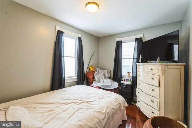 bedroom with multiple windows and dark hardwood / wood-style flooring