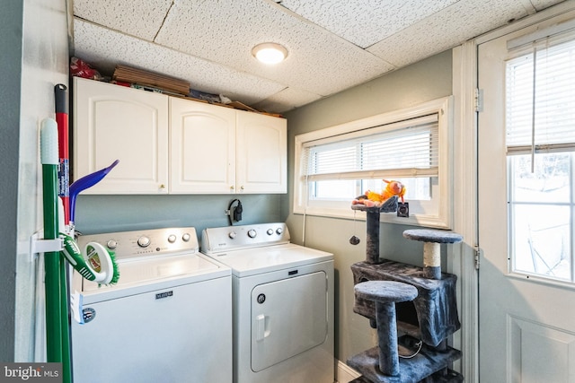 clothes washing area with separate washer and dryer and cabinets