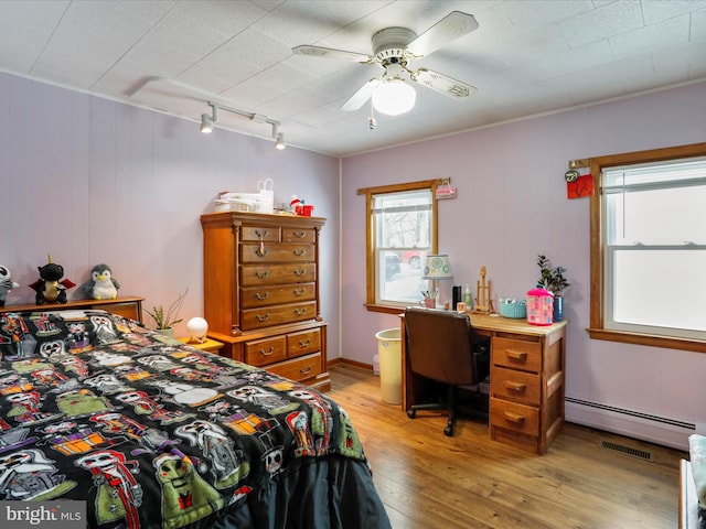 bedroom featuring ceiling fan, baseboard heating, rail lighting, and light hardwood / wood-style flooring