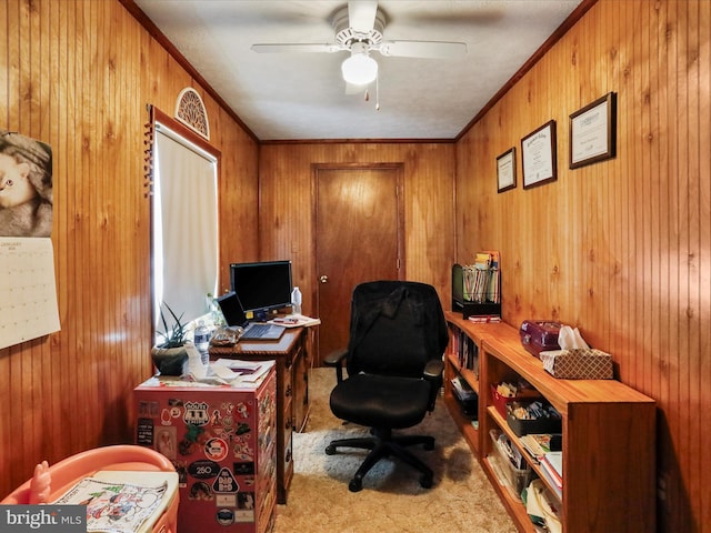 carpeted office space with wooden walls, ceiling fan, and crown molding