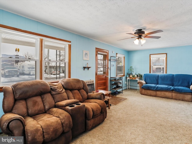 living room featuring carpet, a textured ceiling, a wall mounted AC, and ceiling fan