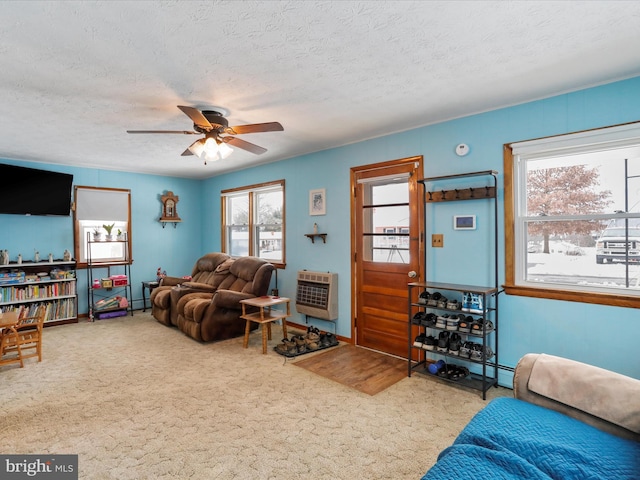 carpeted living room featuring a textured ceiling, heating unit, and a healthy amount of sunlight