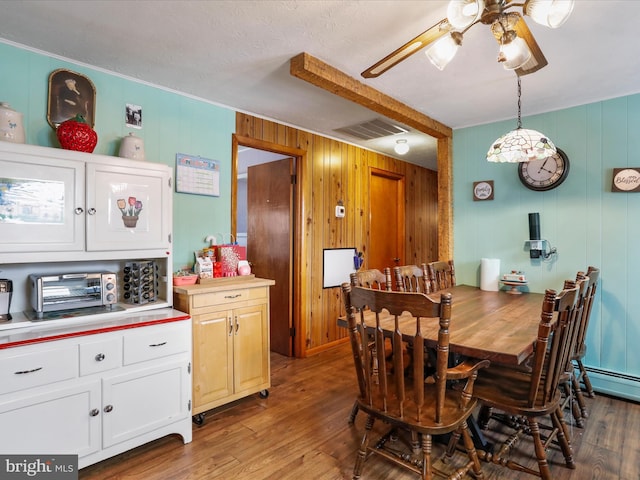 dining space with hardwood / wood-style flooring, ceiling fan, and wooden walls