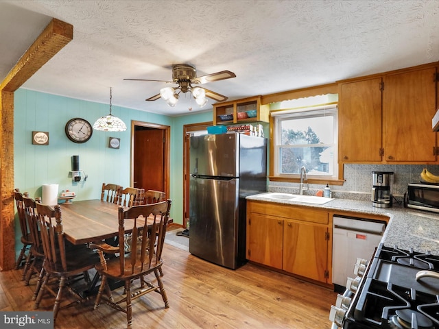 kitchen with sink, light hardwood / wood-style flooring, ceiling fan, appliances with stainless steel finishes, and decorative light fixtures