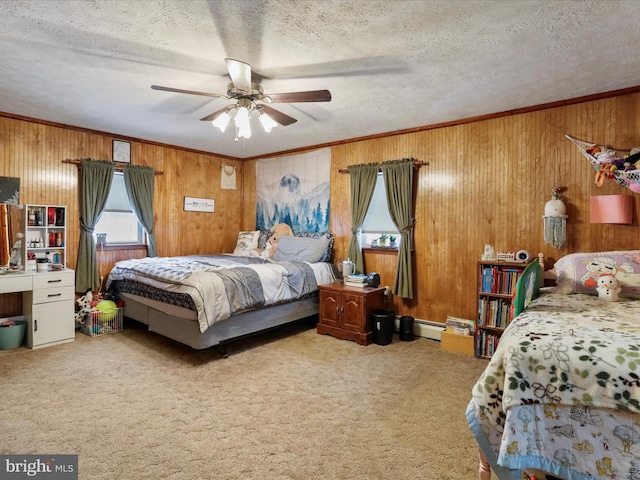 carpeted bedroom featuring a baseboard heating unit, wooden walls, ceiling fan, ornamental molding, and a textured ceiling