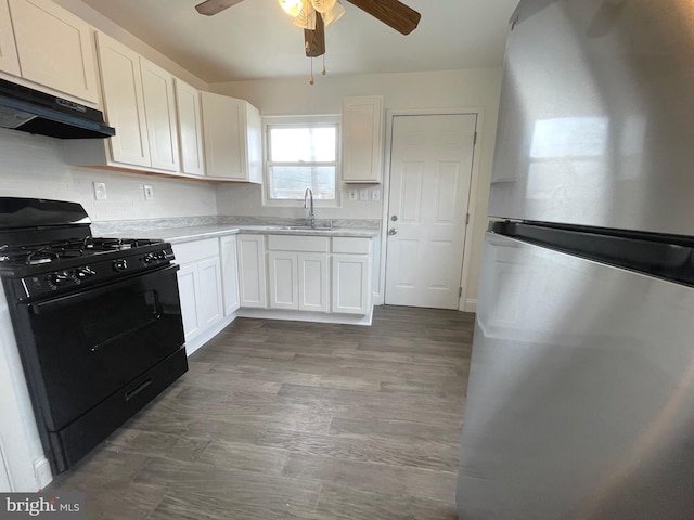 kitchen featuring hardwood / wood-style floors, stainless steel refrigerator, white cabinetry, sink, and black range with gas cooktop