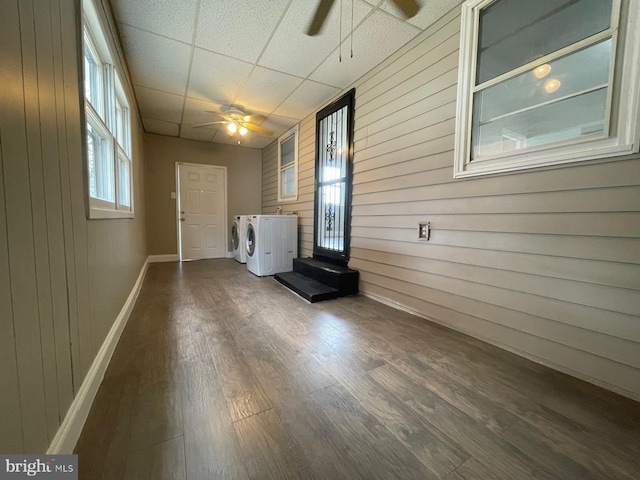 interior space featuring washer and dryer, dark wood-type flooring, ceiling fan, and wood walls