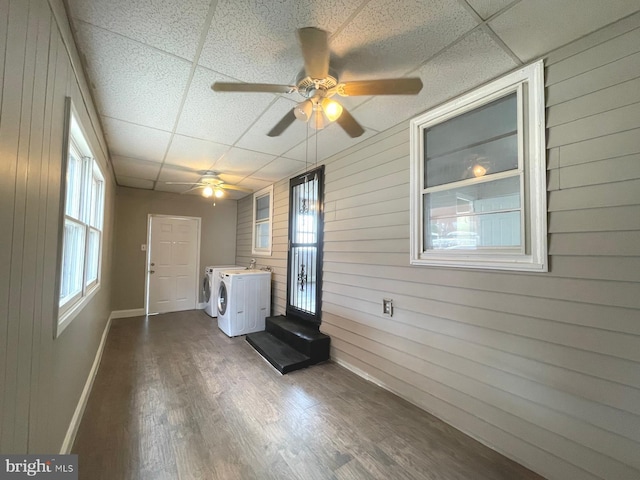 interior space featuring ceiling fan, hardwood / wood-style flooring, wooden walls, and washing machine and clothes dryer