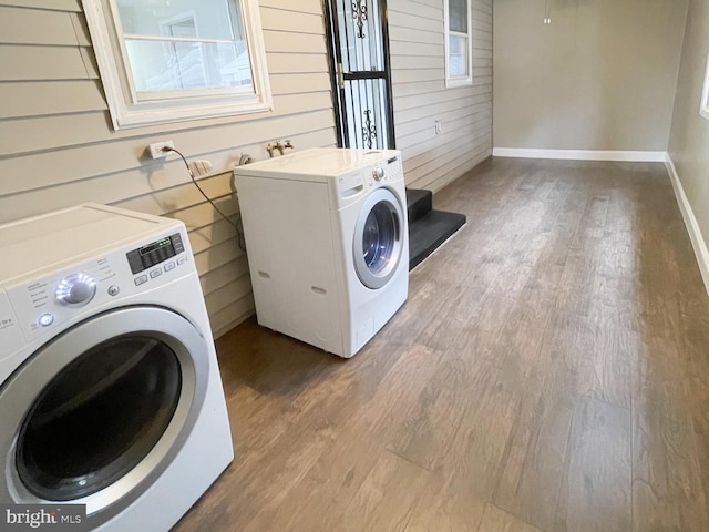 laundry area featuring hardwood / wood-style floors, wooden walls, and washing machine and clothes dryer