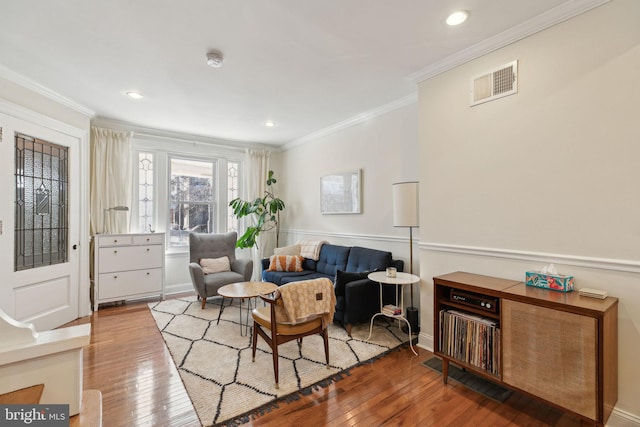 living area with light wood-type flooring, visible vents, and crown molding