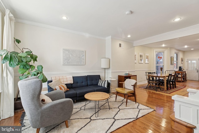 living area with light wood-style floors, visible vents, ornamental molding, and recessed lighting