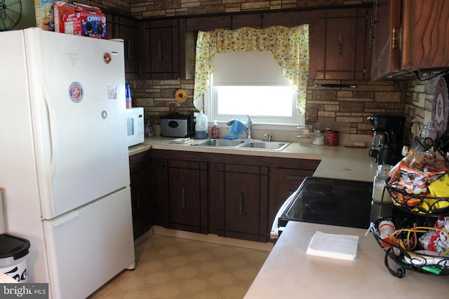 kitchen featuring dark brown cabinetry, tasteful backsplash, sink, and white appliances