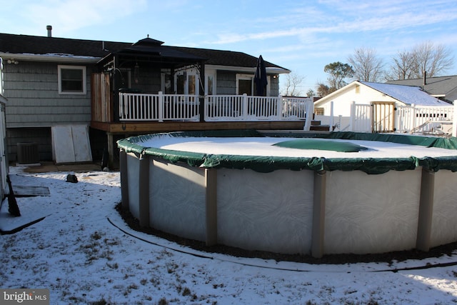 snow covered house featuring a pool side deck and central AC unit