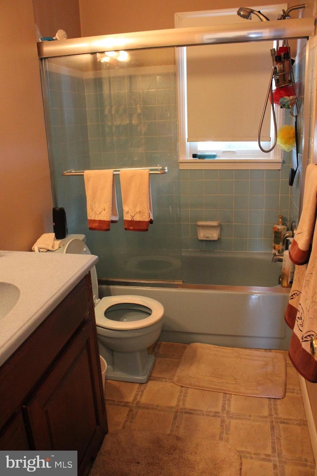 full bathroom featuring bath / shower combo with glass door, vanity, and toilet