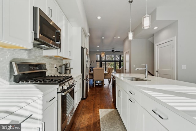 kitchen featuring sink, ceiling fan, appliances with stainless steel finishes, decorative light fixtures, and white cabinetry