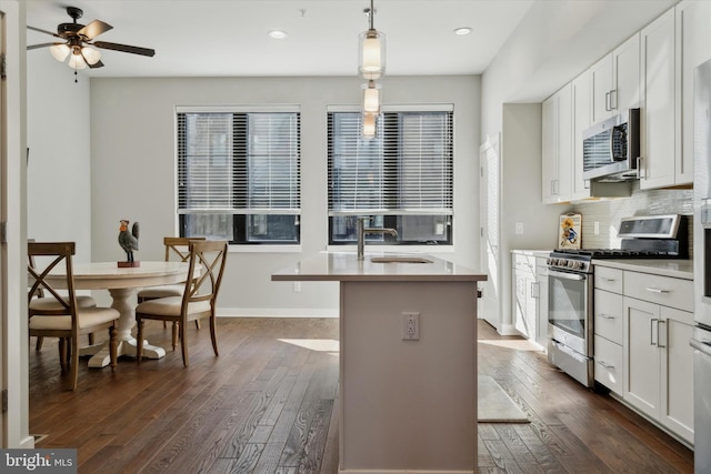 kitchen with white cabinetry, sink, hanging light fixtures, a kitchen island with sink, and appliances with stainless steel finishes