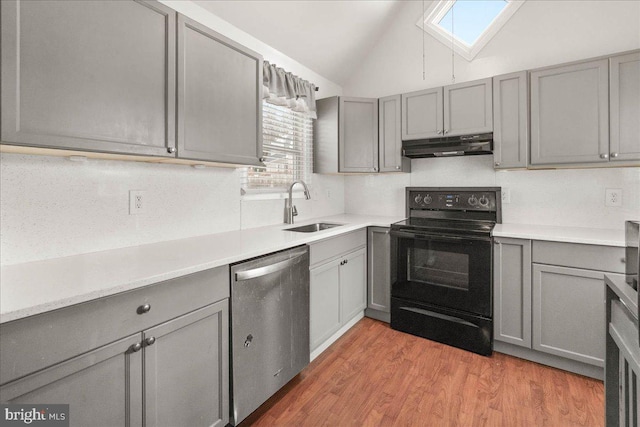 kitchen featuring vaulted ceiling with skylight, black range with electric cooktop, sink, dishwasher, and gray cabinets