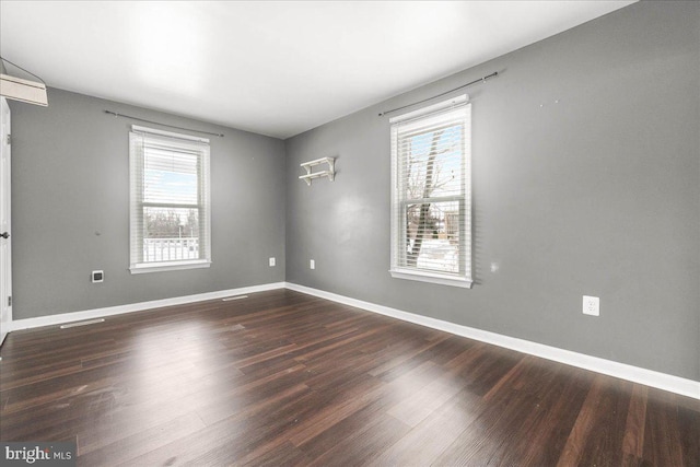 spare room with plenty of natural light and dark hardwood / wood-style floors