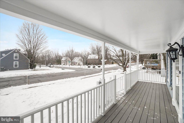 snow covered deck featuring a porch