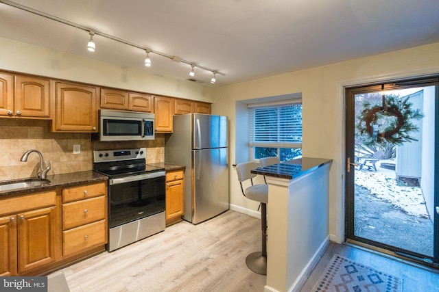 kitchen with light wood-type flooring, stainless steel appliances, tasteful backsplash, and sink