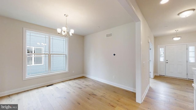 foyer with light hardwood / wood-style floors and a notable chandelier