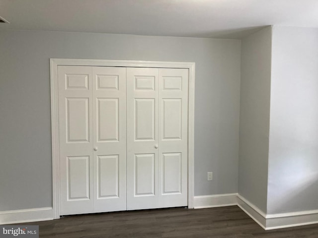 unfurnished bedroom featuring dark hardwood / wood-style flooring and a closet