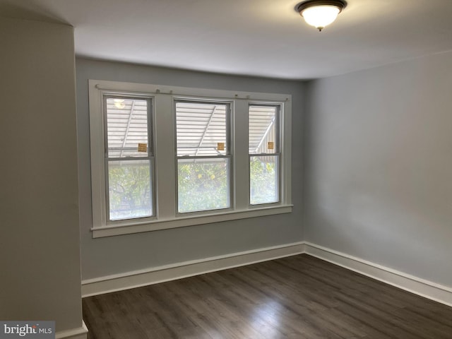 empty room with dark wood-type flooring and a wealth of natural light