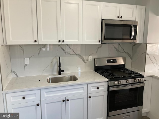 kitchen featuring backsplash, stainless steel appliances, white cabinetry, and sink