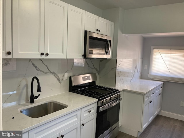 kitchen featuring light stone countertops, tasteful backsplash, stainless steel appliances, sink, and white cabinetry