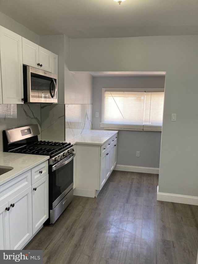 kitchen with dark hardwood / wood-style flooring, backsplash, stainless steel appliances, and white cabinetry