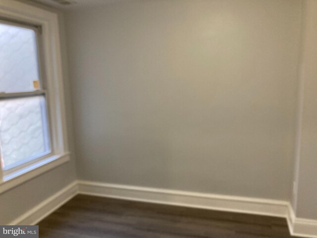 spare room with a healthy amount of sunlight and dark wood-type flooring